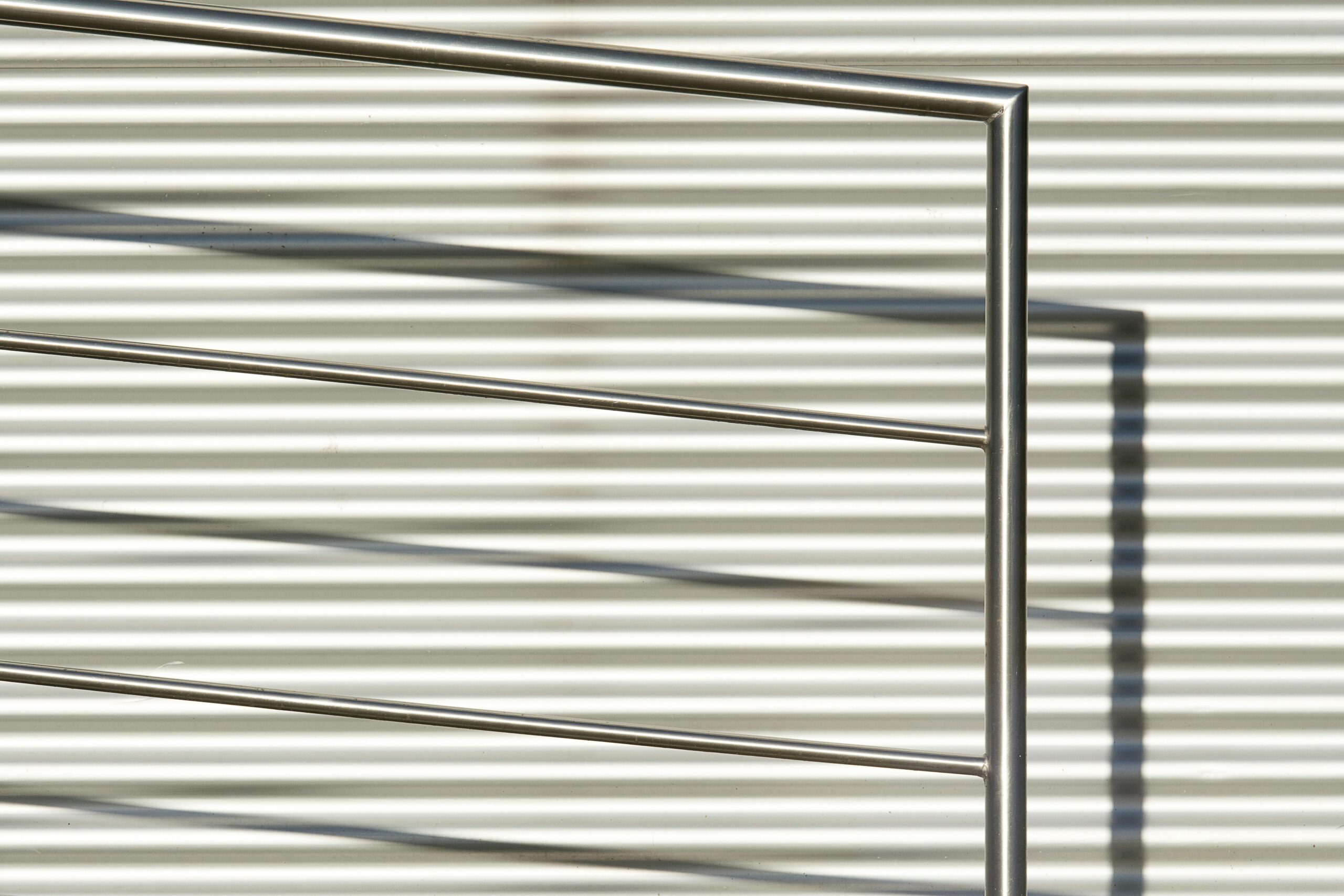 Close-up of a modern stainless steel railing against a striped wall background.